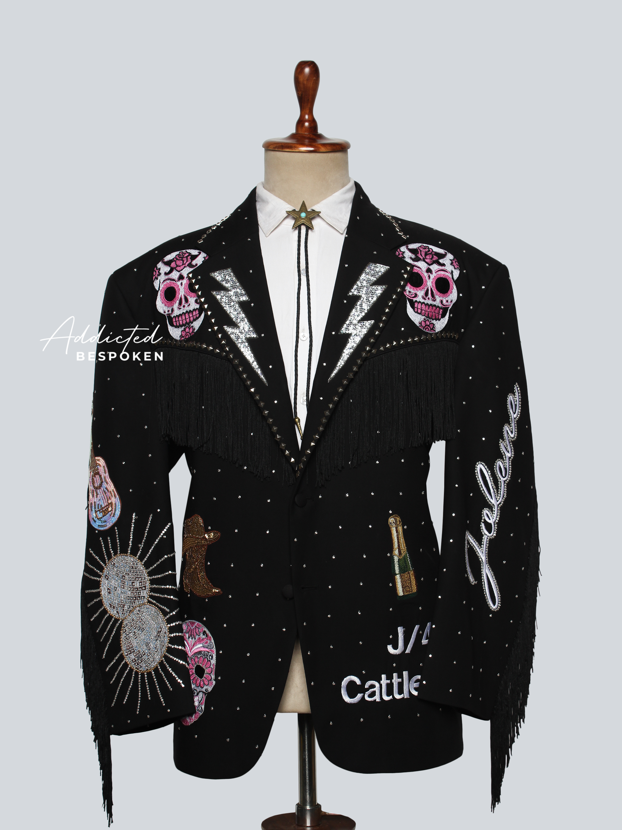 Black blazer with colorful designs and text on a mannequin against a light gray background
