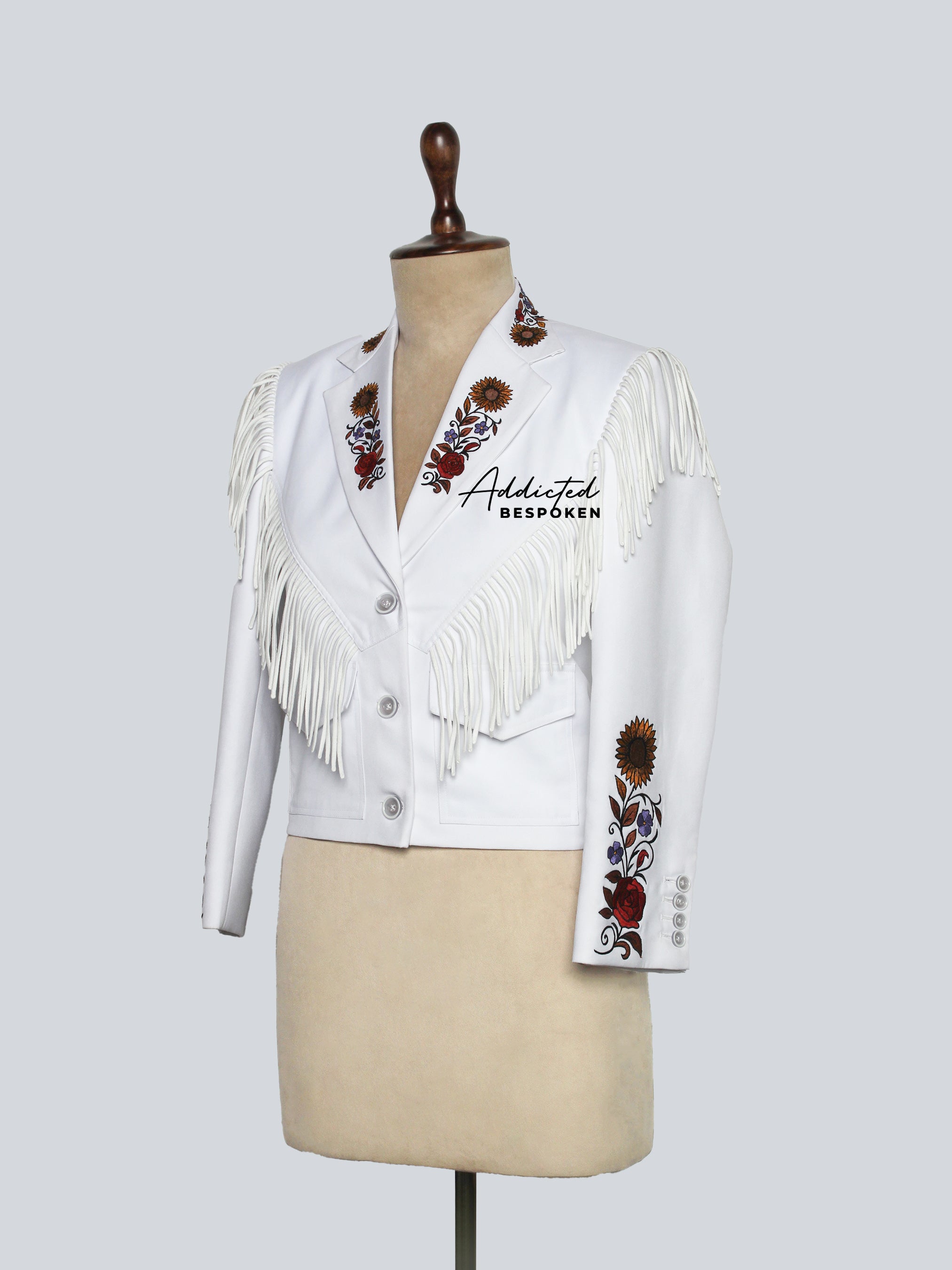 Side View of White jacket with fringe and floral embroidery on a mannequin against a light gray background