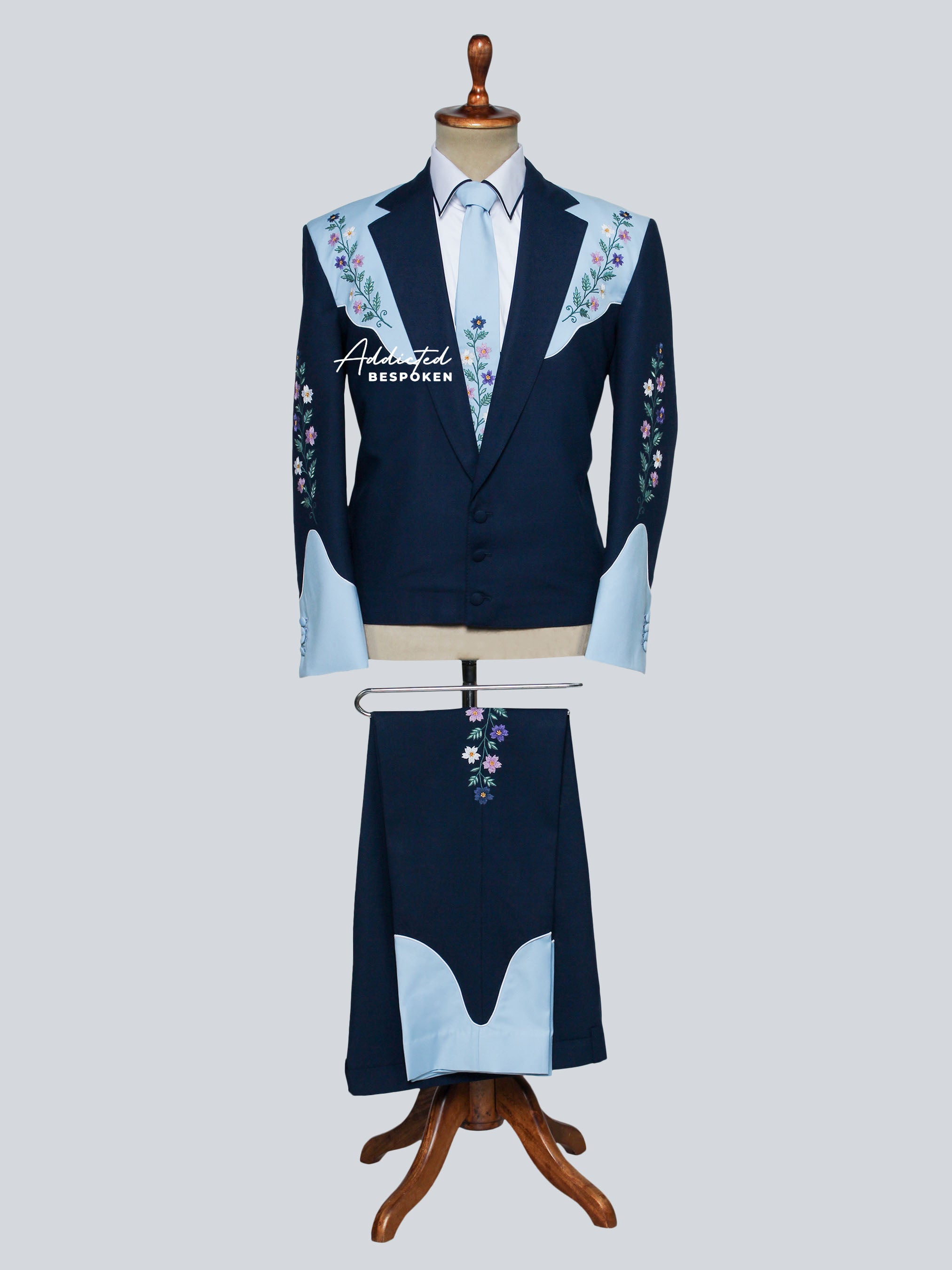 Navy blazer and pant set with floral embroidery on a mannequin against a light gray background