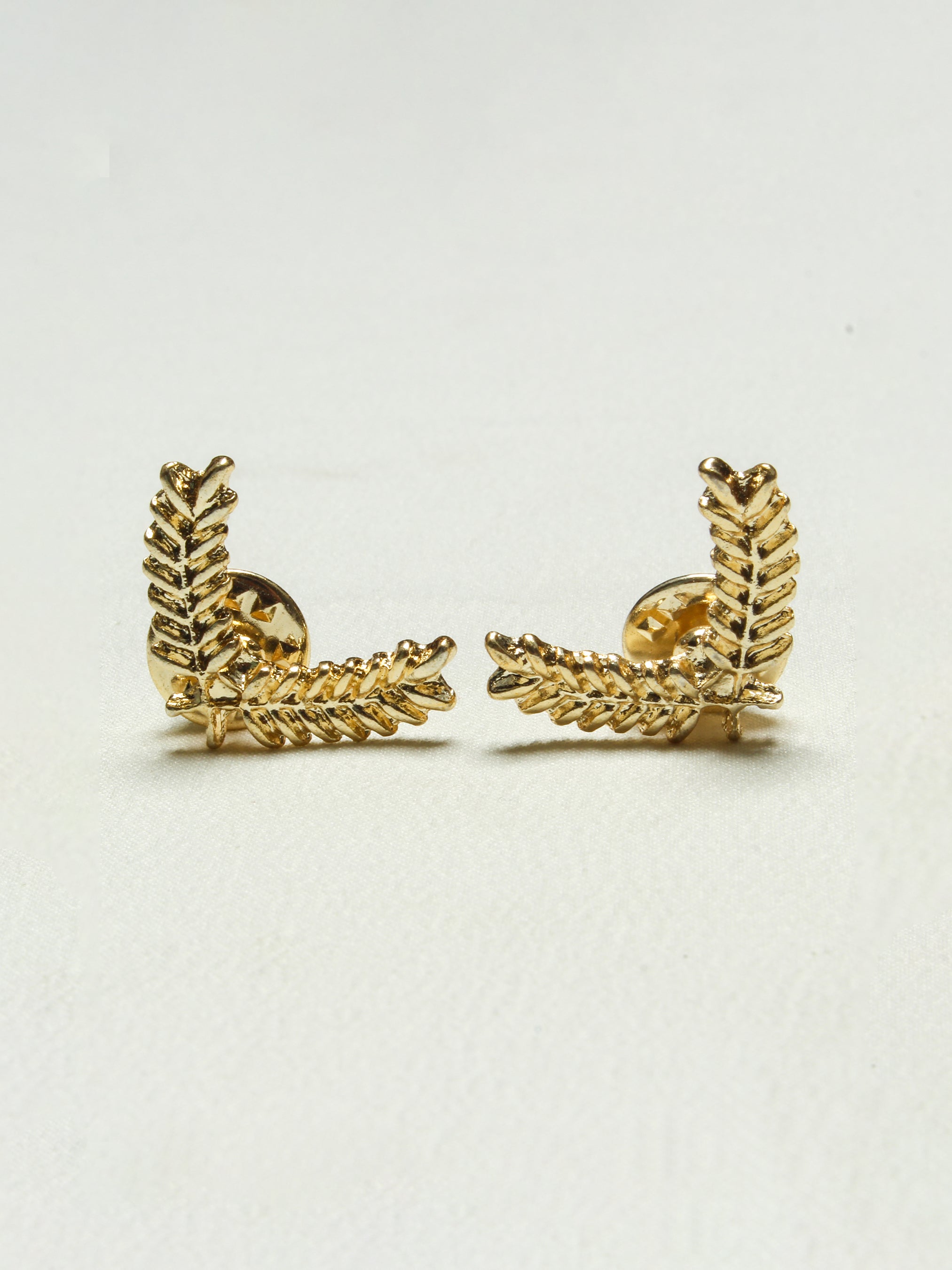 Pair of gold leaf-shaped cufflinks from Addicted Bespoken displayed on a white background