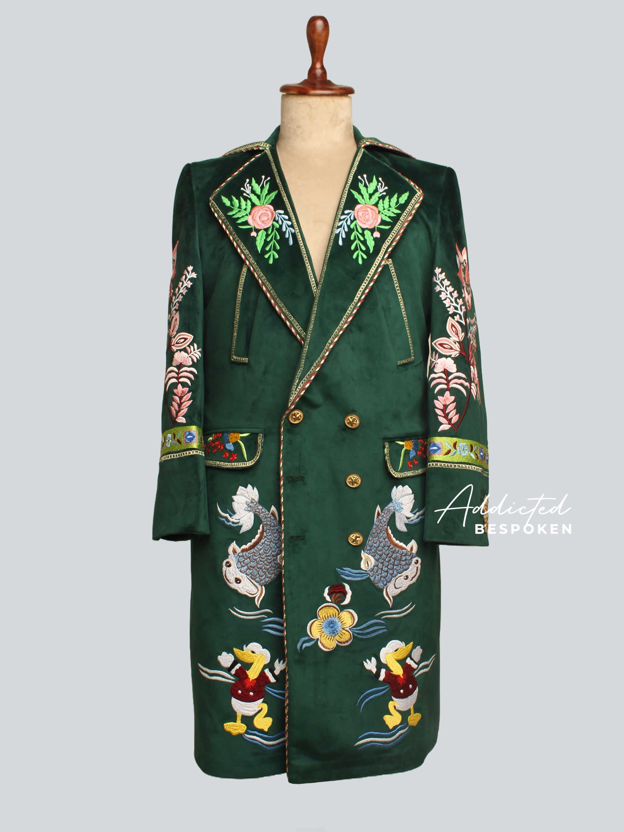 Emerald green embroidered double-breasted statement coat with koi fish and floral motifs from Addicted Bespoken on a mannequin
