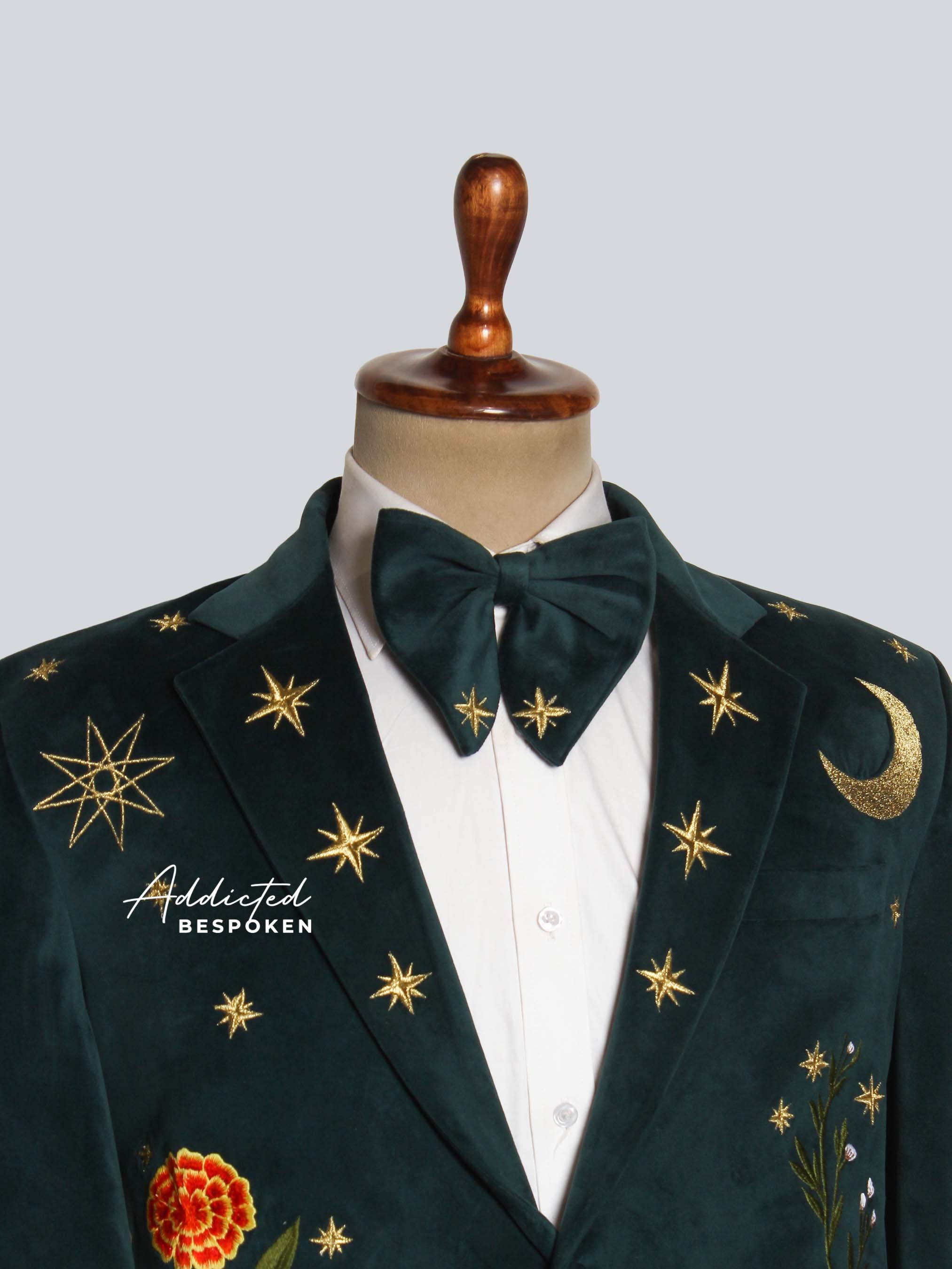 Green embroidered blazer with gold stars and floral designs on a mannequin against a light gray background.