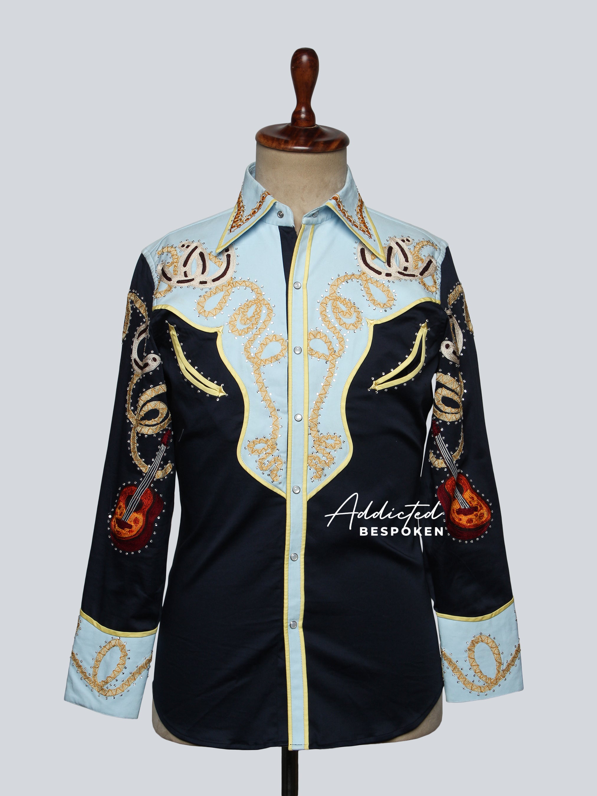A navy-colored statement shirt with intricate gold and orange embroidery, displayed on a mannequin.