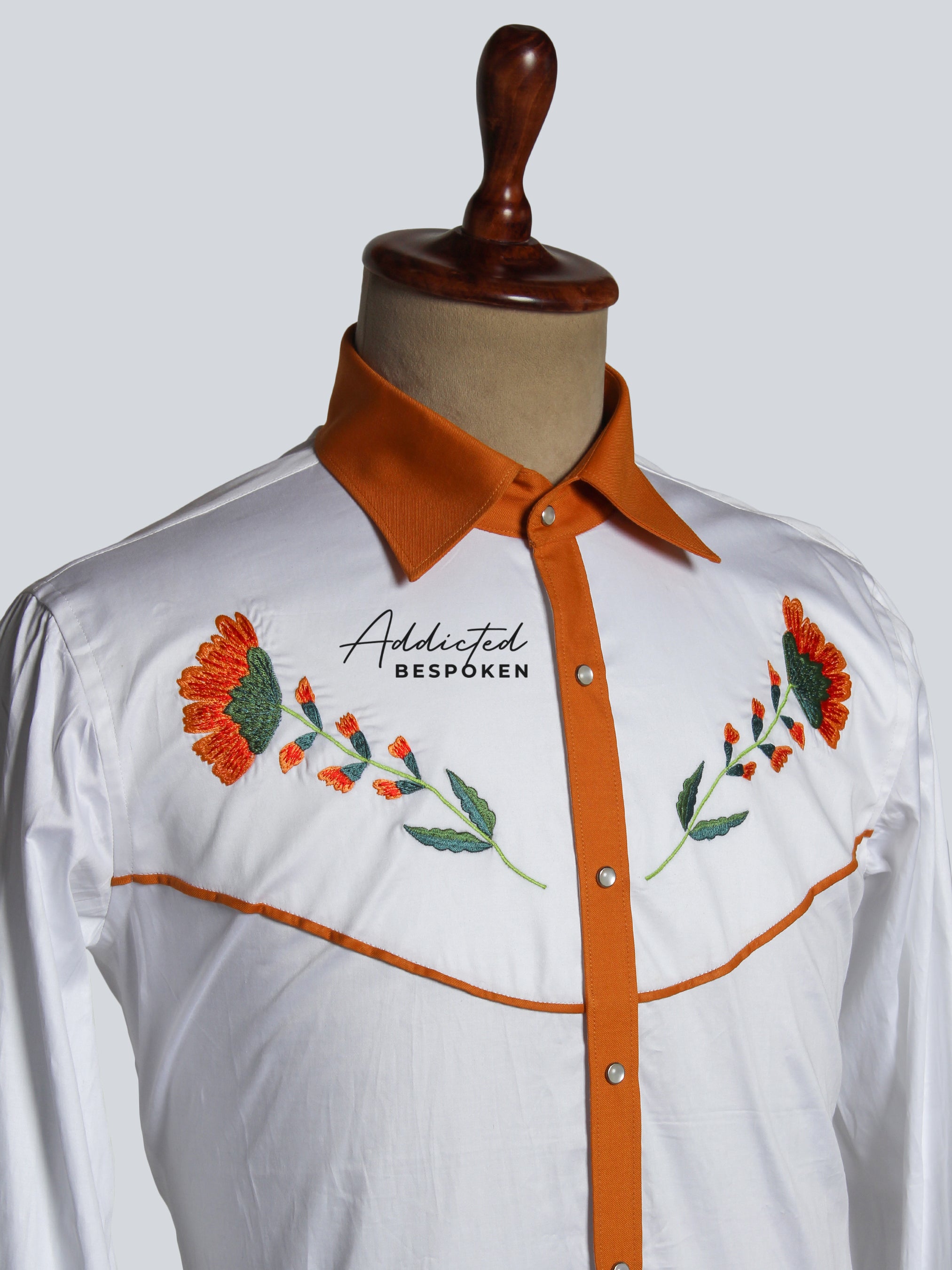 Close-up chest view of white western shirt with orange piping and floral embroidery โ Addicted Bespoken