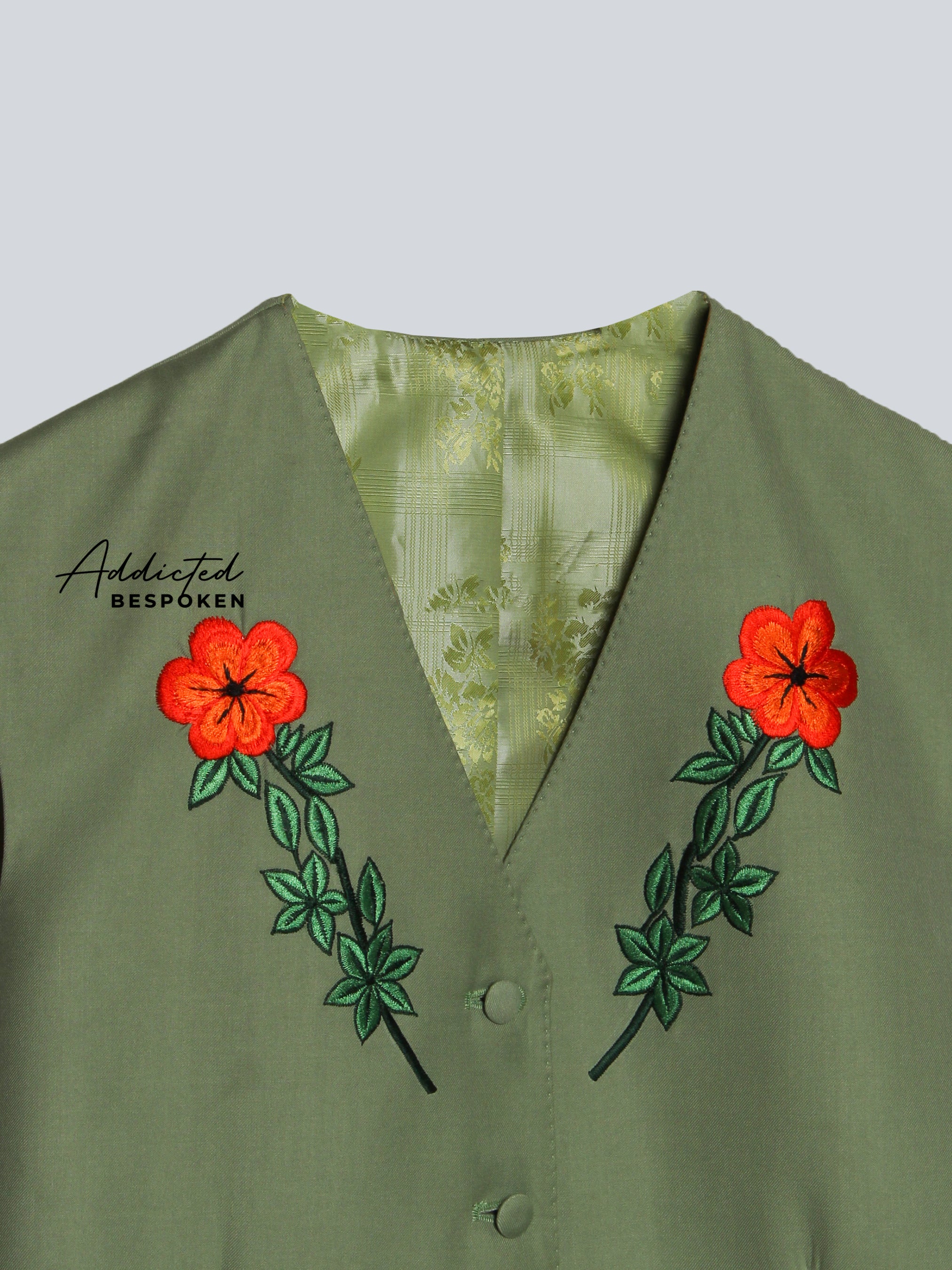 Green jacket with red floral embroidery on a light gray background