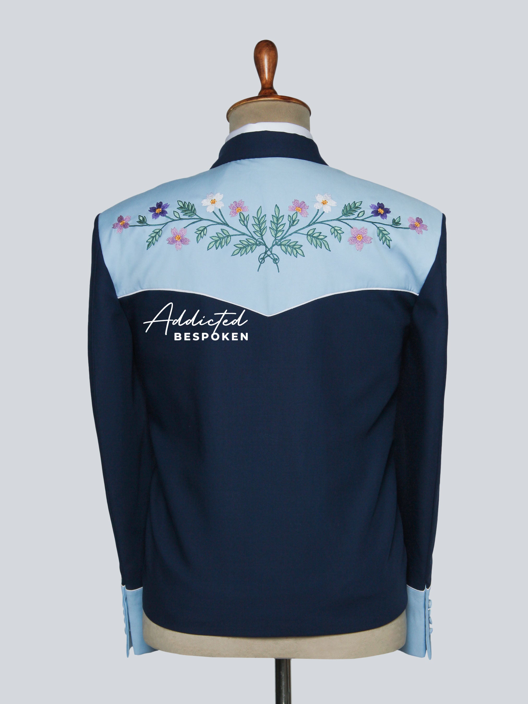 Navy jacket with floral embroidery on a mannequin against a light gray background