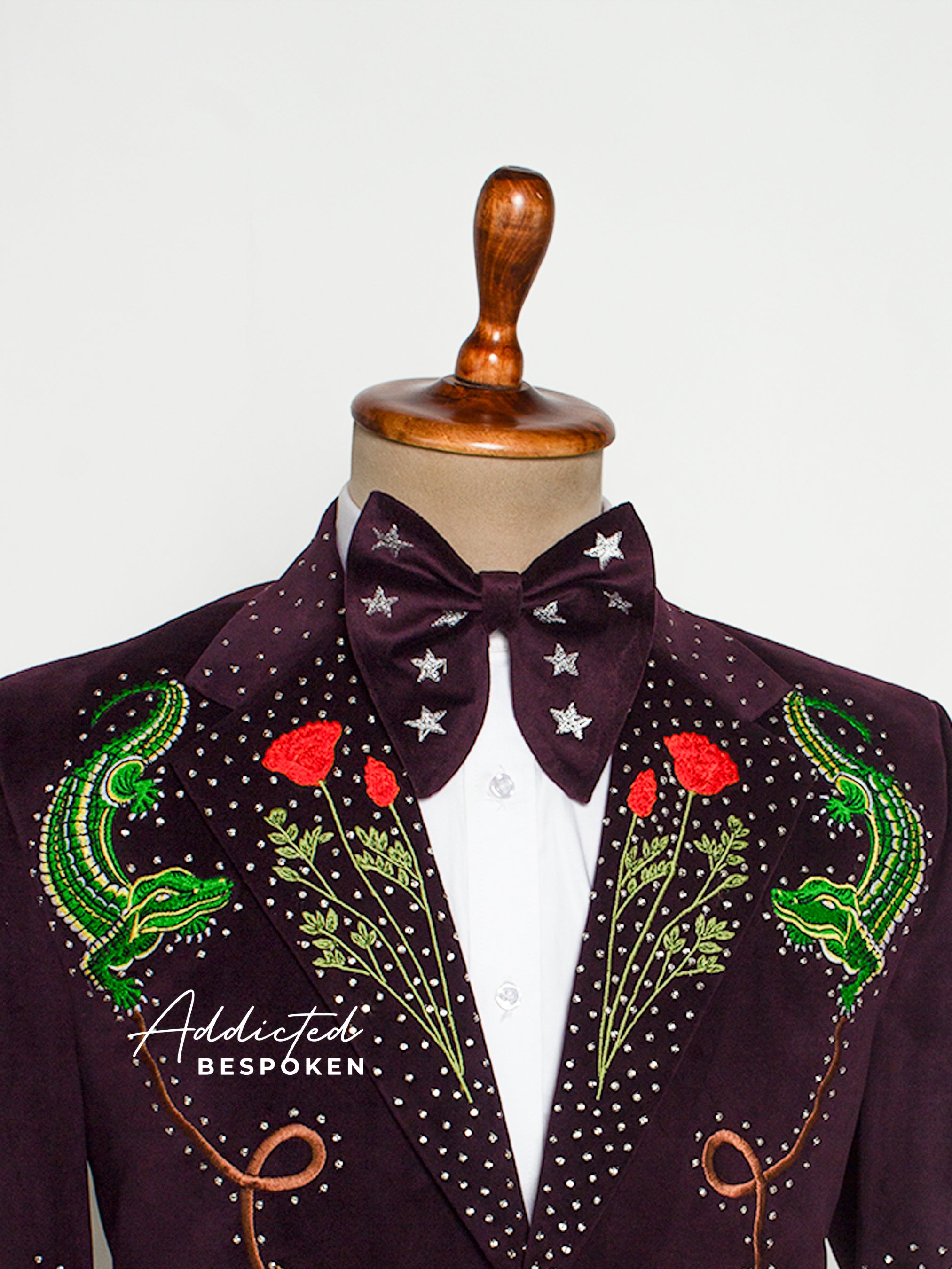 Embroidered jacket with floral and lizard designs on a mannequin against a white background