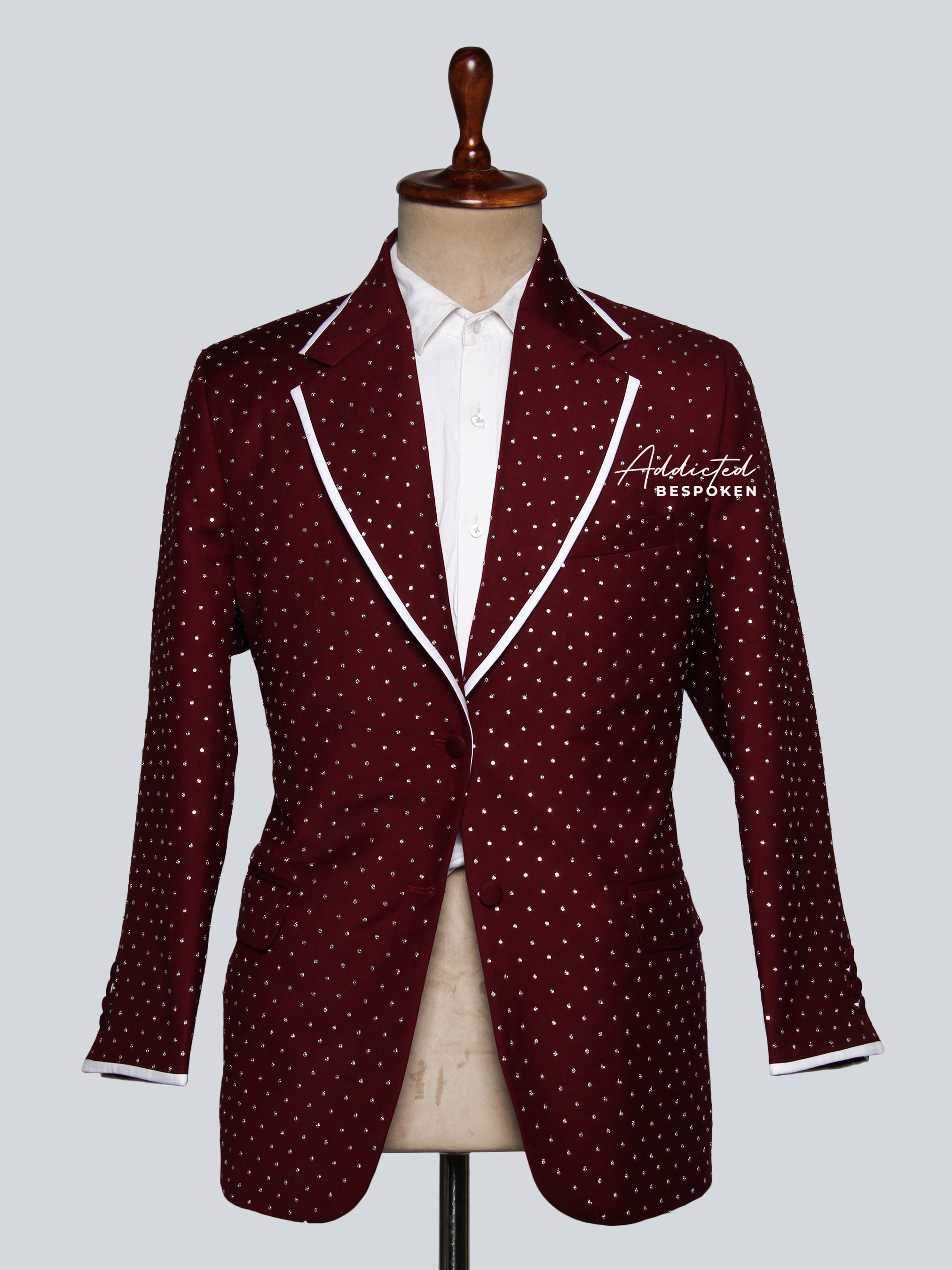 A tailored blazer with a two-button closure, crisp white lapels, and a subtle red dotted pattern on a mannequin. The blazer features functional pockets and a notched lapel.