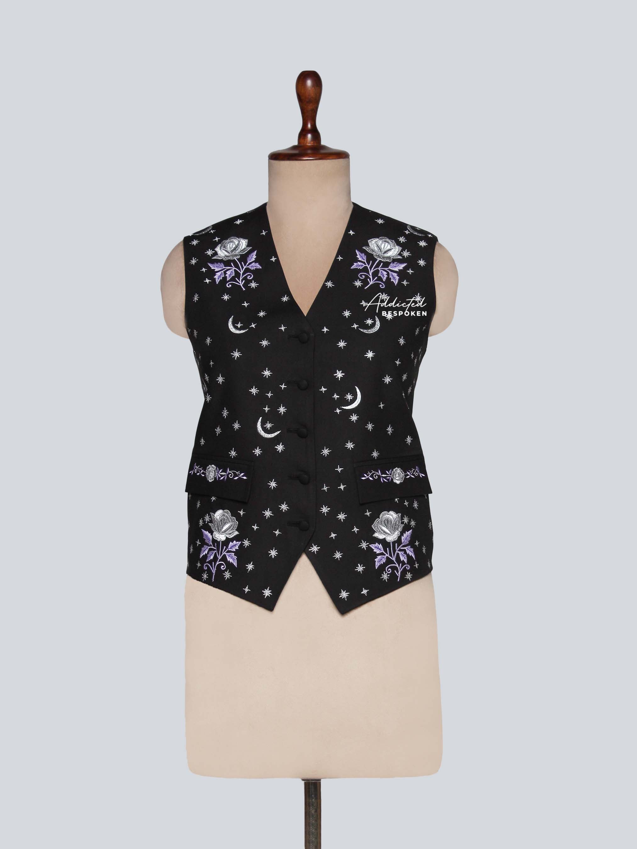 Black vest with floral and celestial patterns on a mannequin against a light gray background