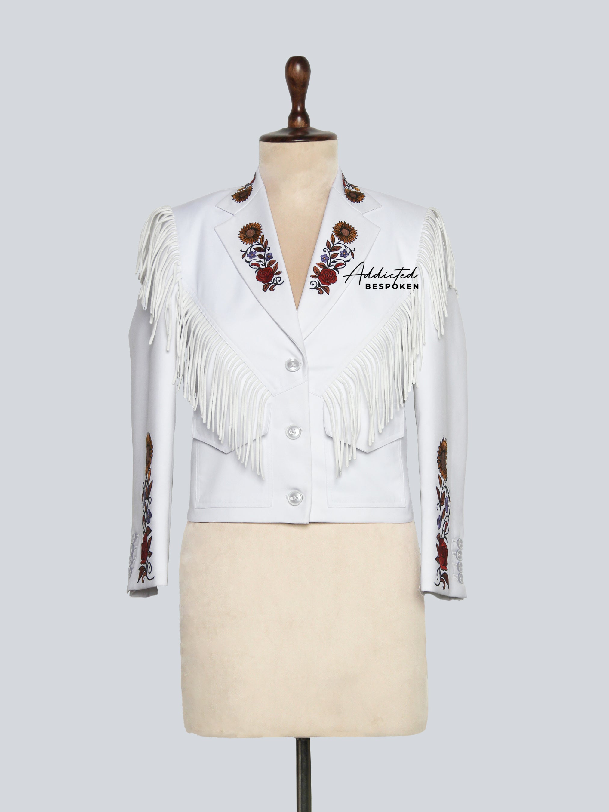White fringed jacket with embroidery on a mannequin against a light gray background