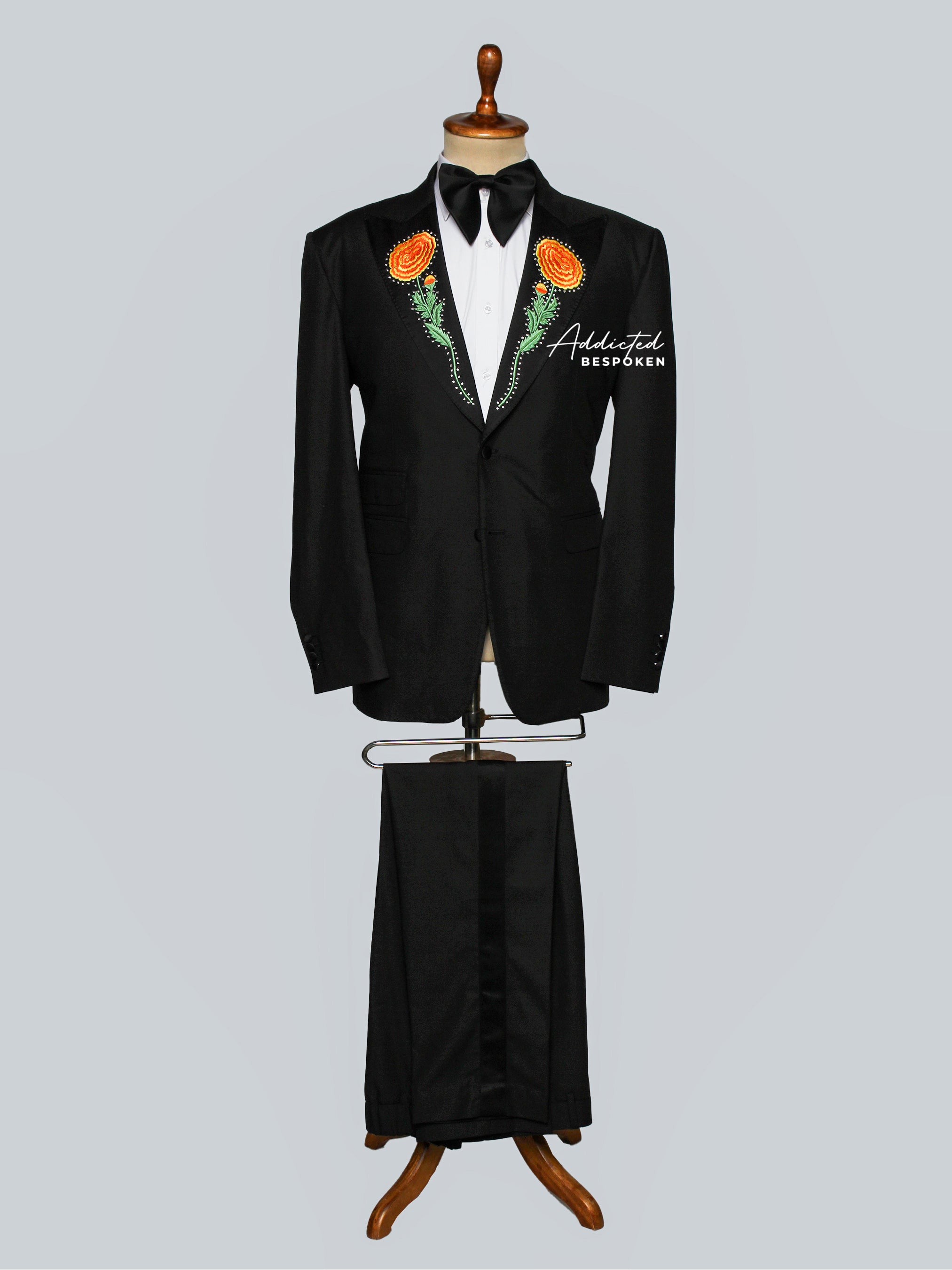 Full View of Black tuxedo with floral decorations on a mannequin against a light gray background