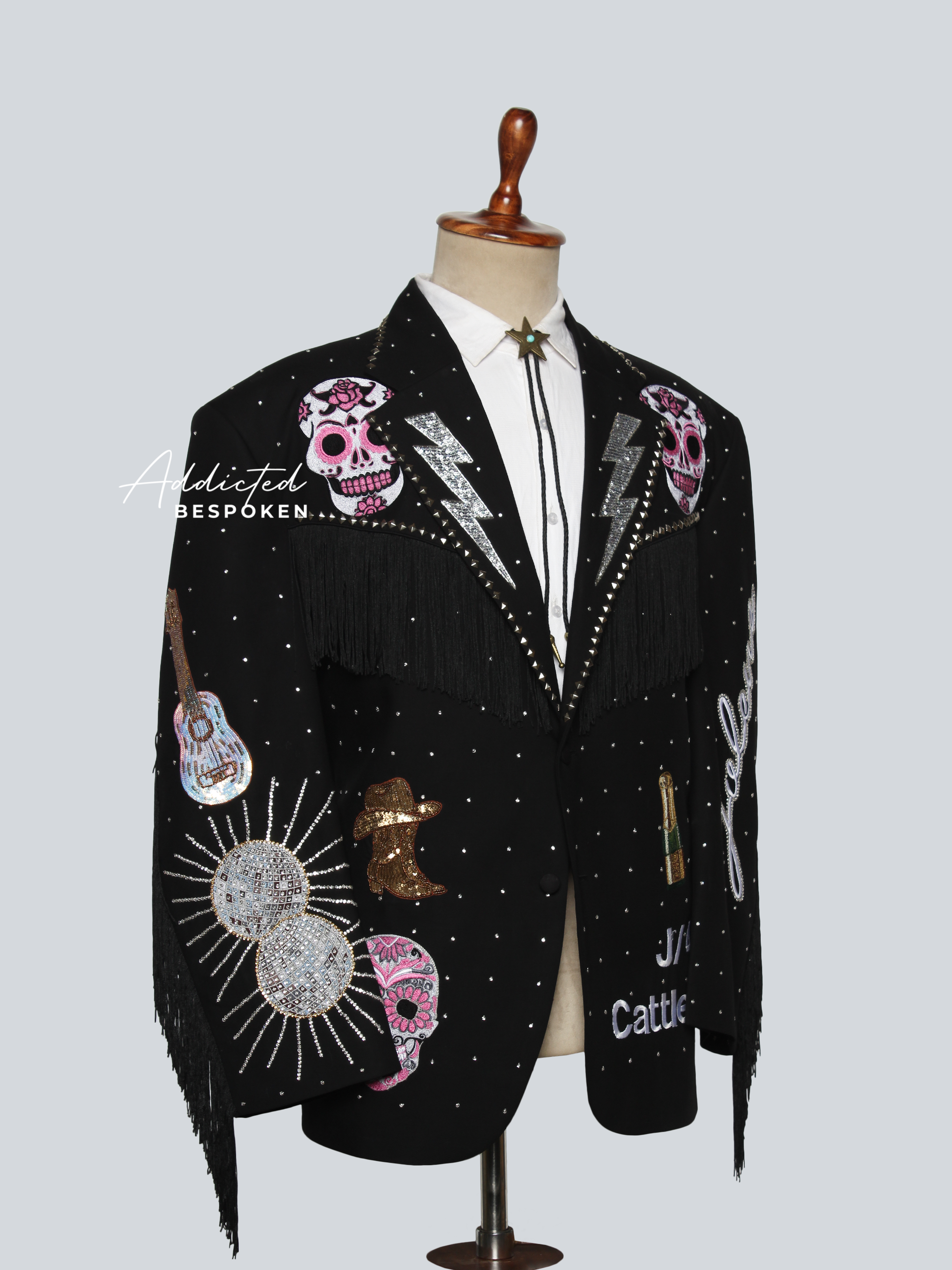 Black blazer with colorful embellishments on a mannequin against a light gray background