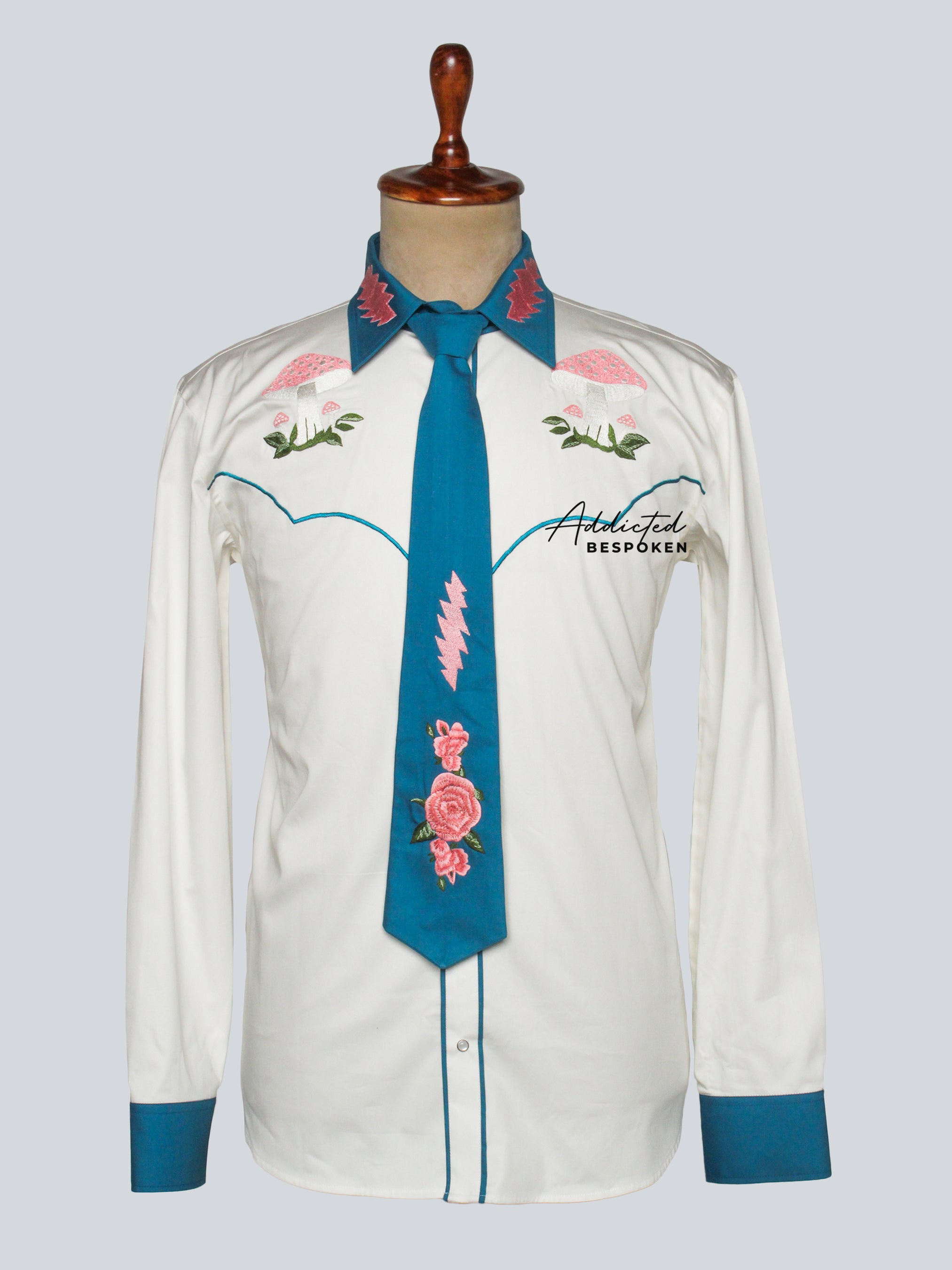Front view of white western shirt with green piping and pink floral embroidery, styled with turquoise embroidered tie – Addicted Bespoken