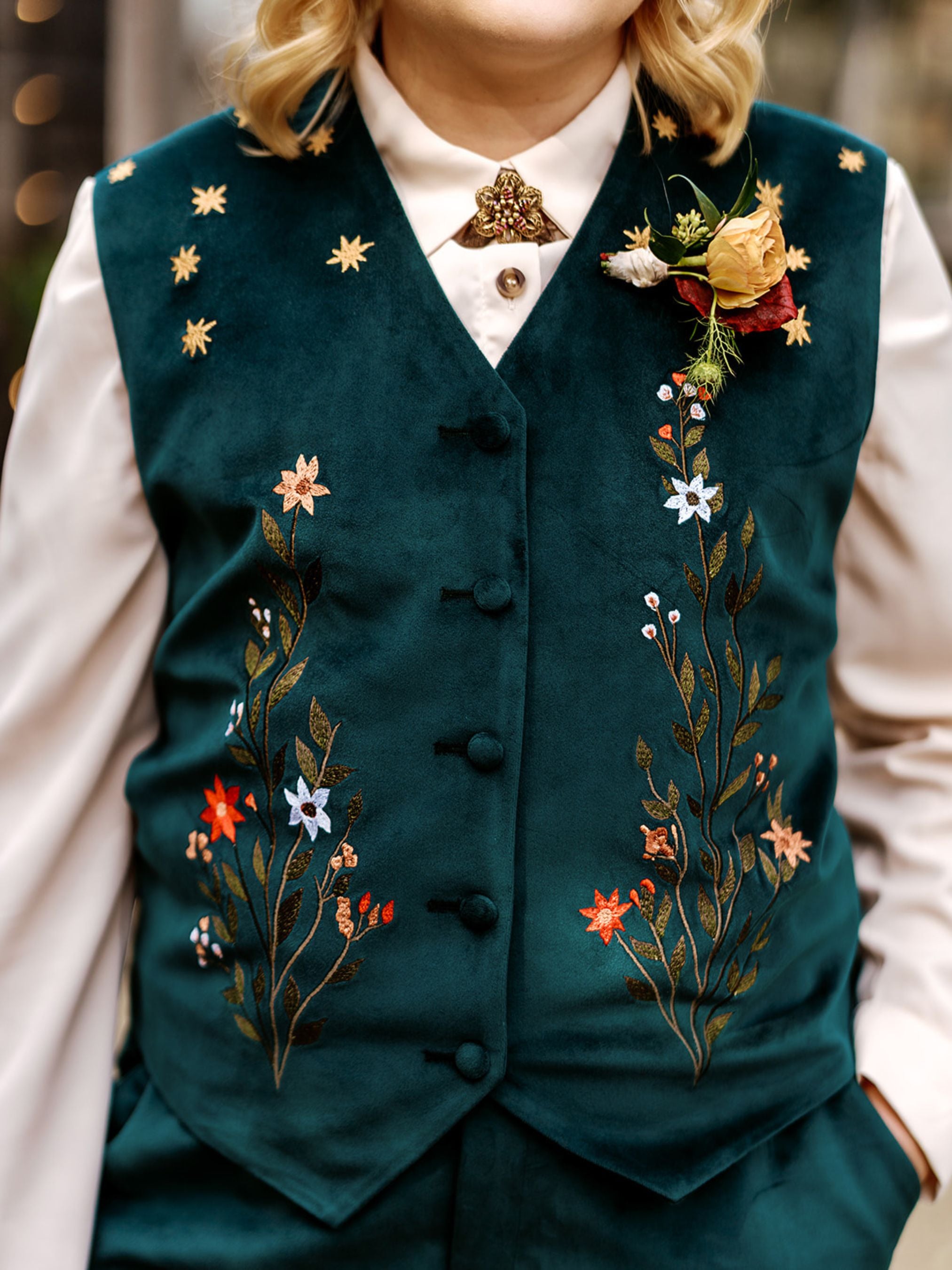 Teal embroidered vest worn by a person with a blurred background