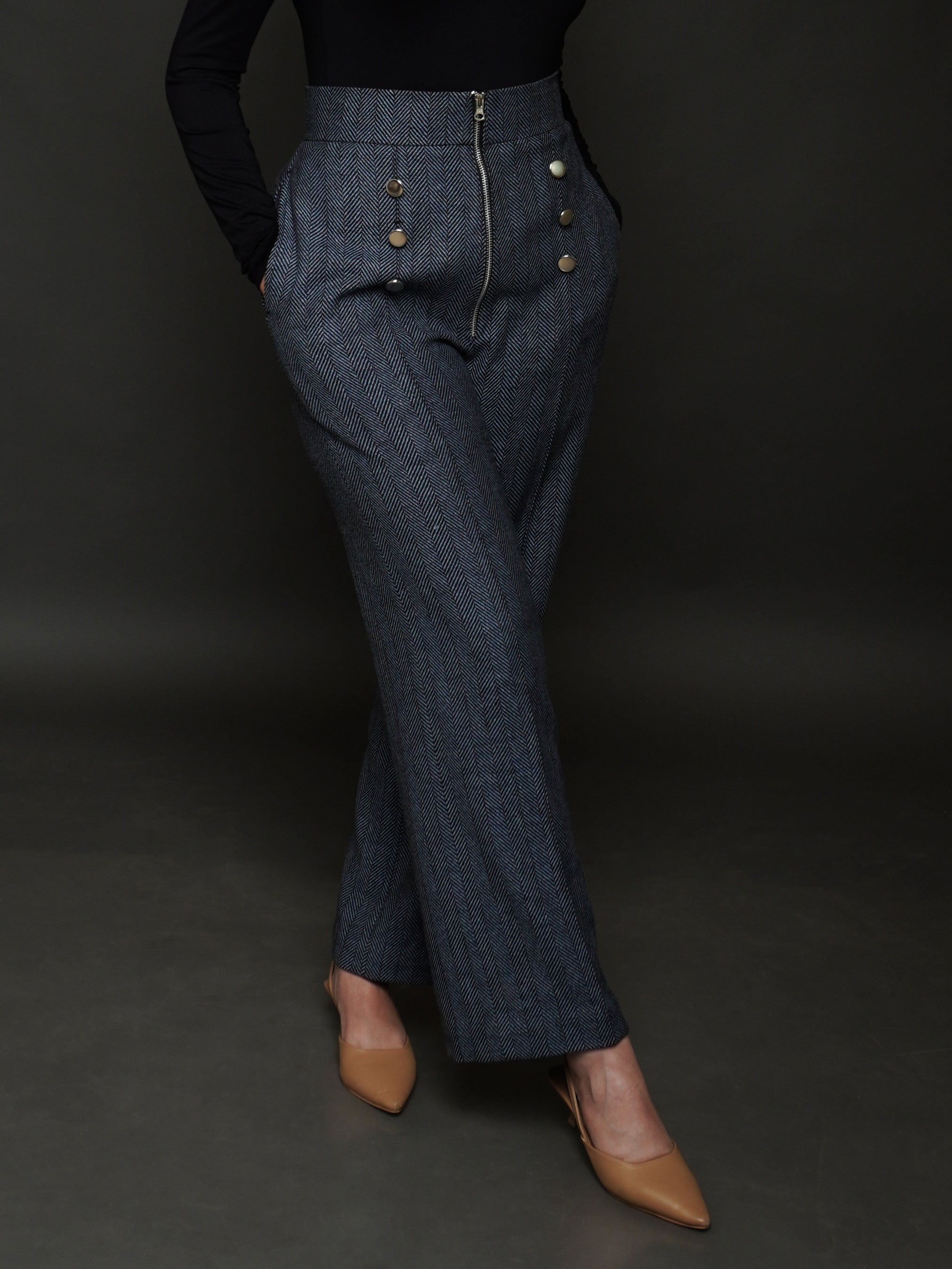 Close-up of woman wearing high-waisted navy patterned wide-leg trousers with gold button details from Addicted Bespoken, styled with nude heels.