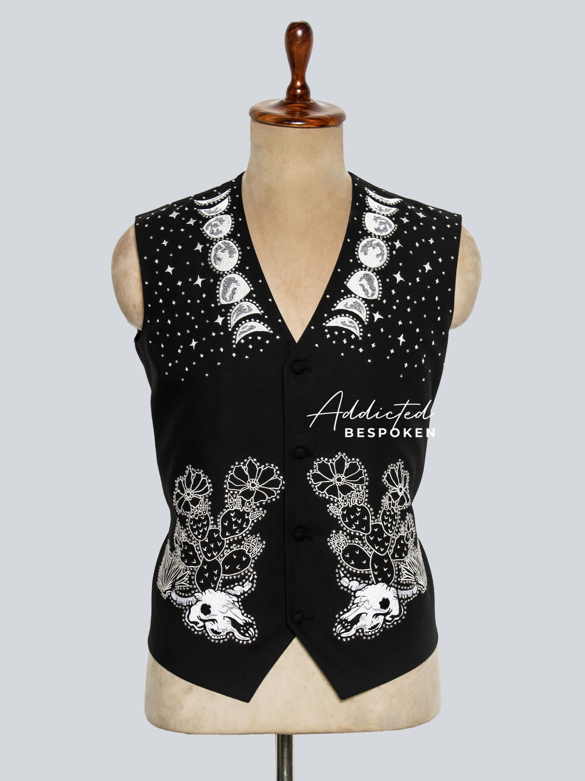 Black vest with white embellishments on a mannequin against a light gray background