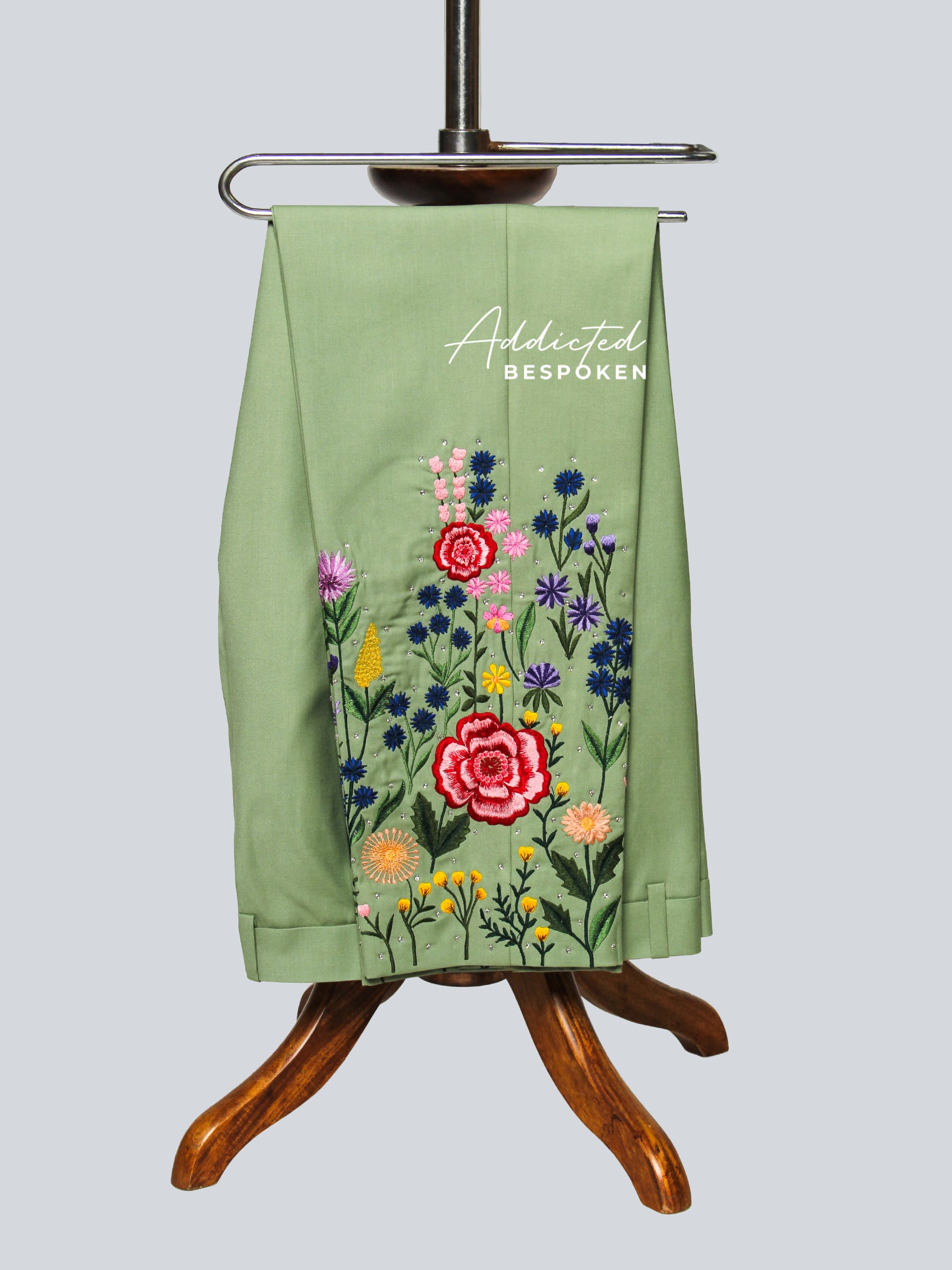 Green apron with floral embroidery on a wooden stand against a light gray background