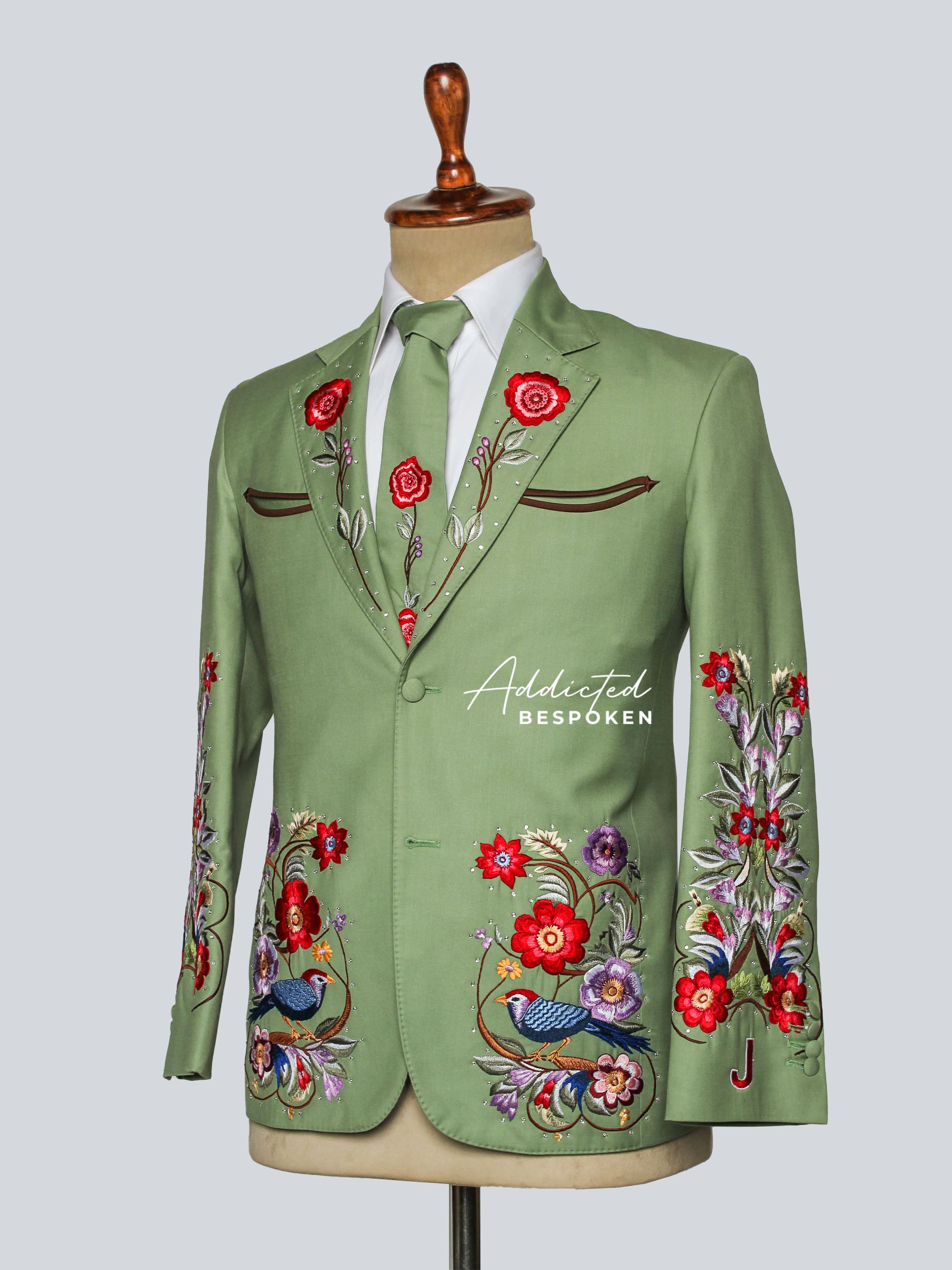 Green embroidered jacket on a mannequin with 'Addicted Bespçken' branding.