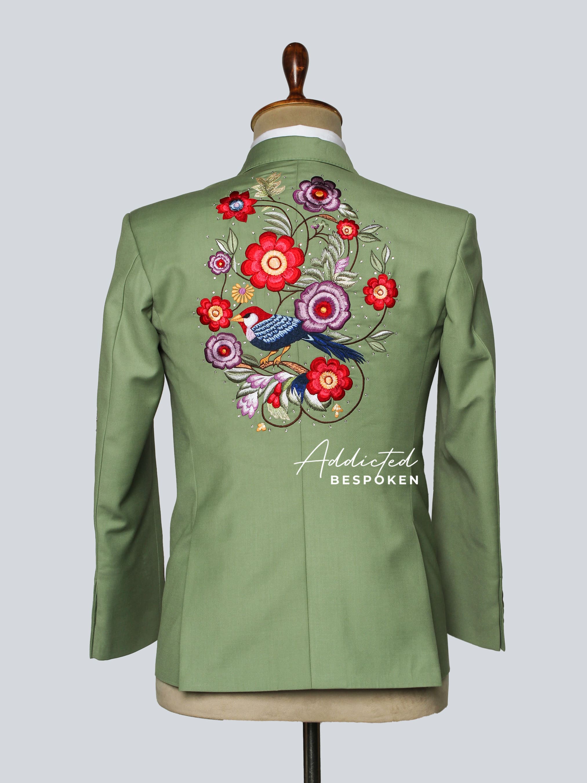 Green jacket with floral embroidery on a mannequin against a light gray background
