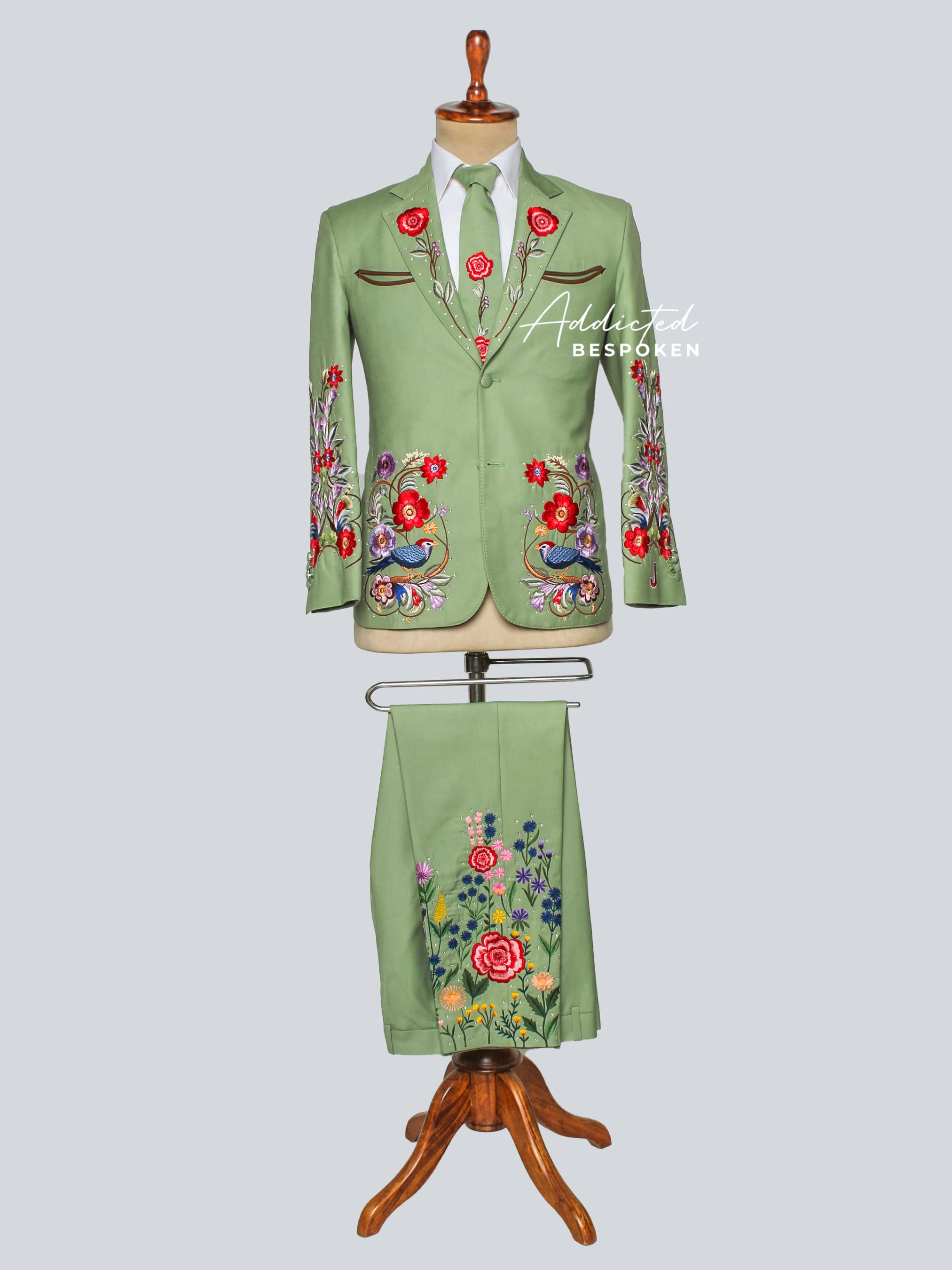 Green embroidered suit on a mannequin against a light gray background