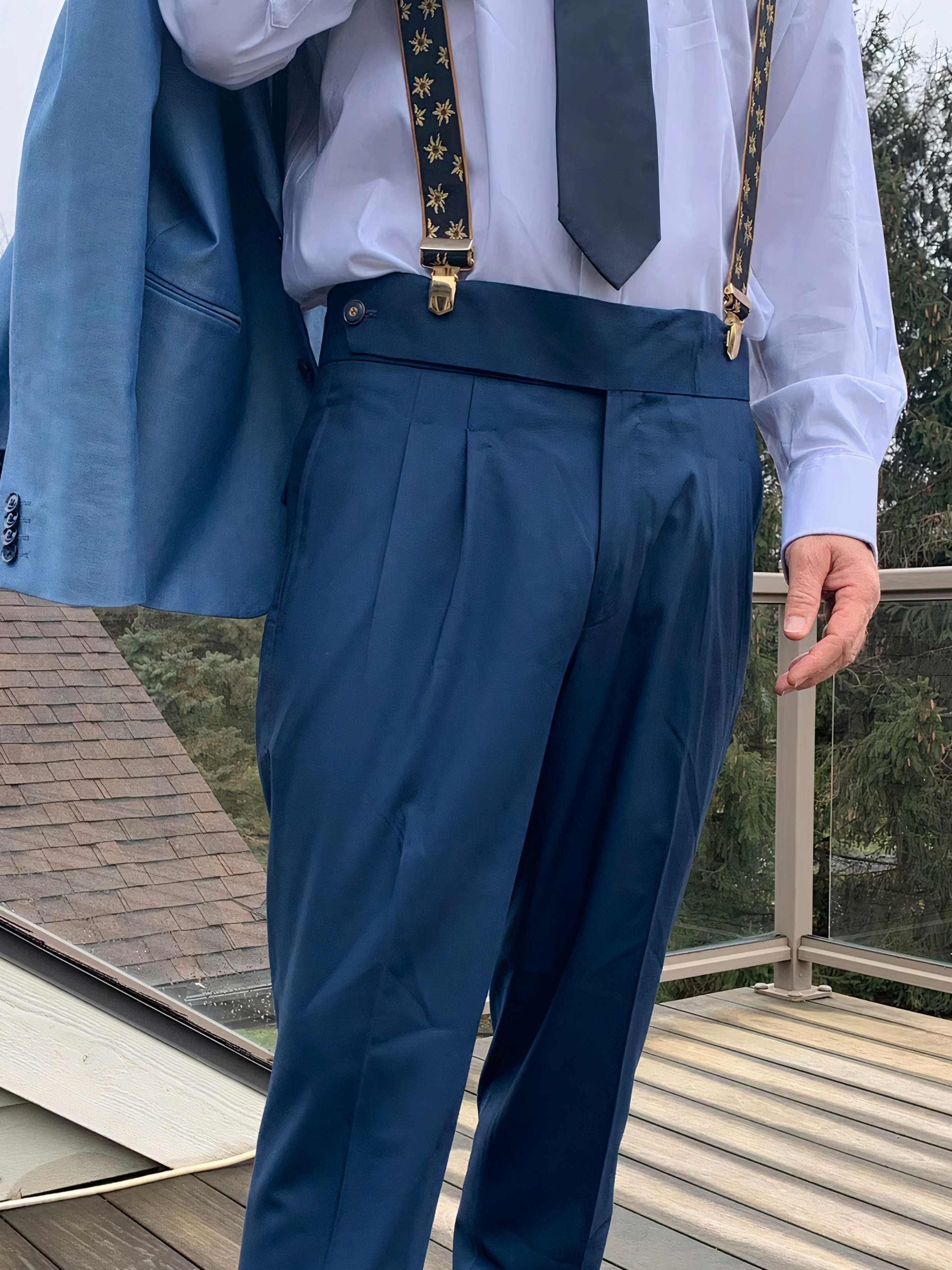 Close-up of man wearing blue high-waisted pleated trousers with braces and a matching suit jacket from Addicted Bespoken.