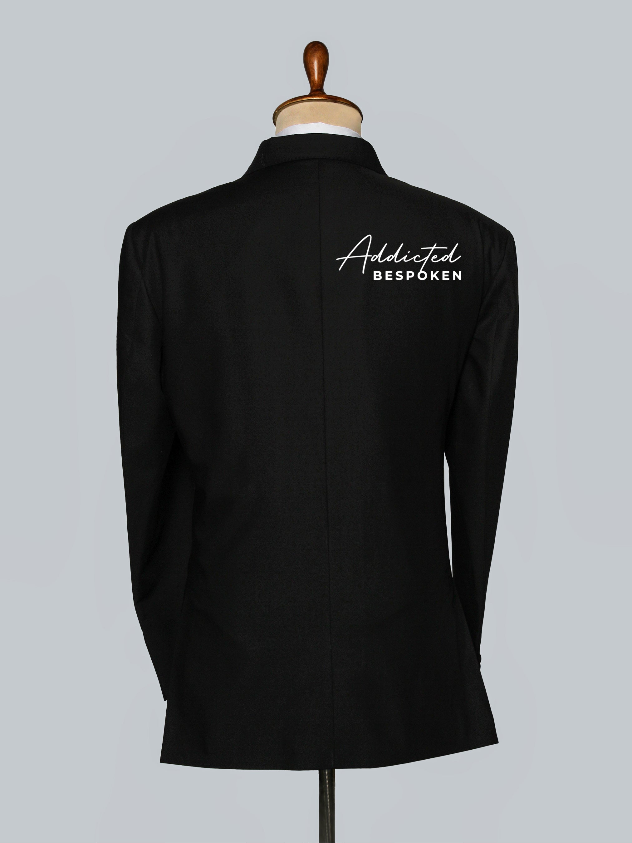 Back View of Black Tuxedo on a mannequin with 'Addicted Bespéoken' branding on a gray background