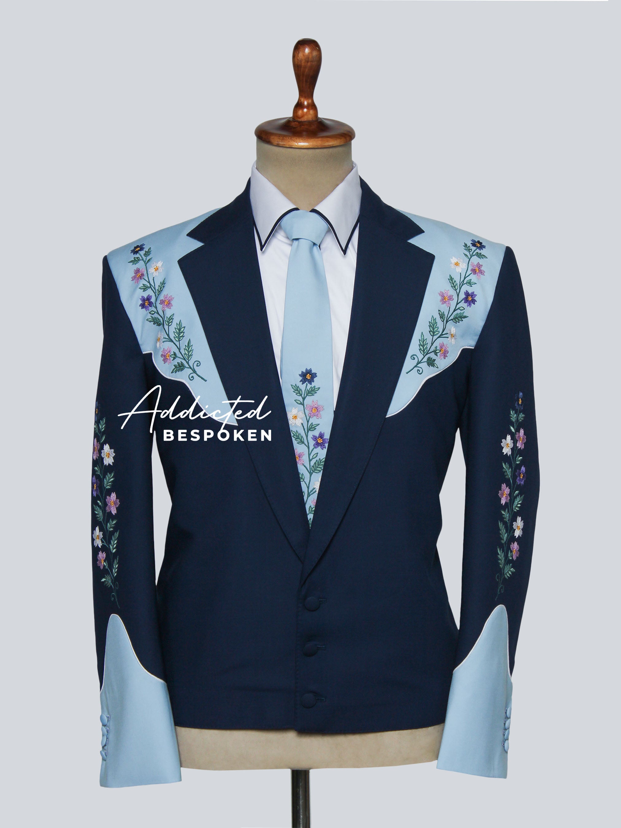 Navy blazer with floral embroidery on a mannequin against a light gray background